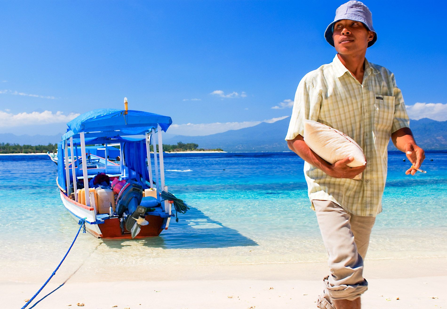 man unloading boat from blue water, island scene, Gili T, Indonesia, small group travel and food photography tours with Sandlin Gaither Explorer's Club