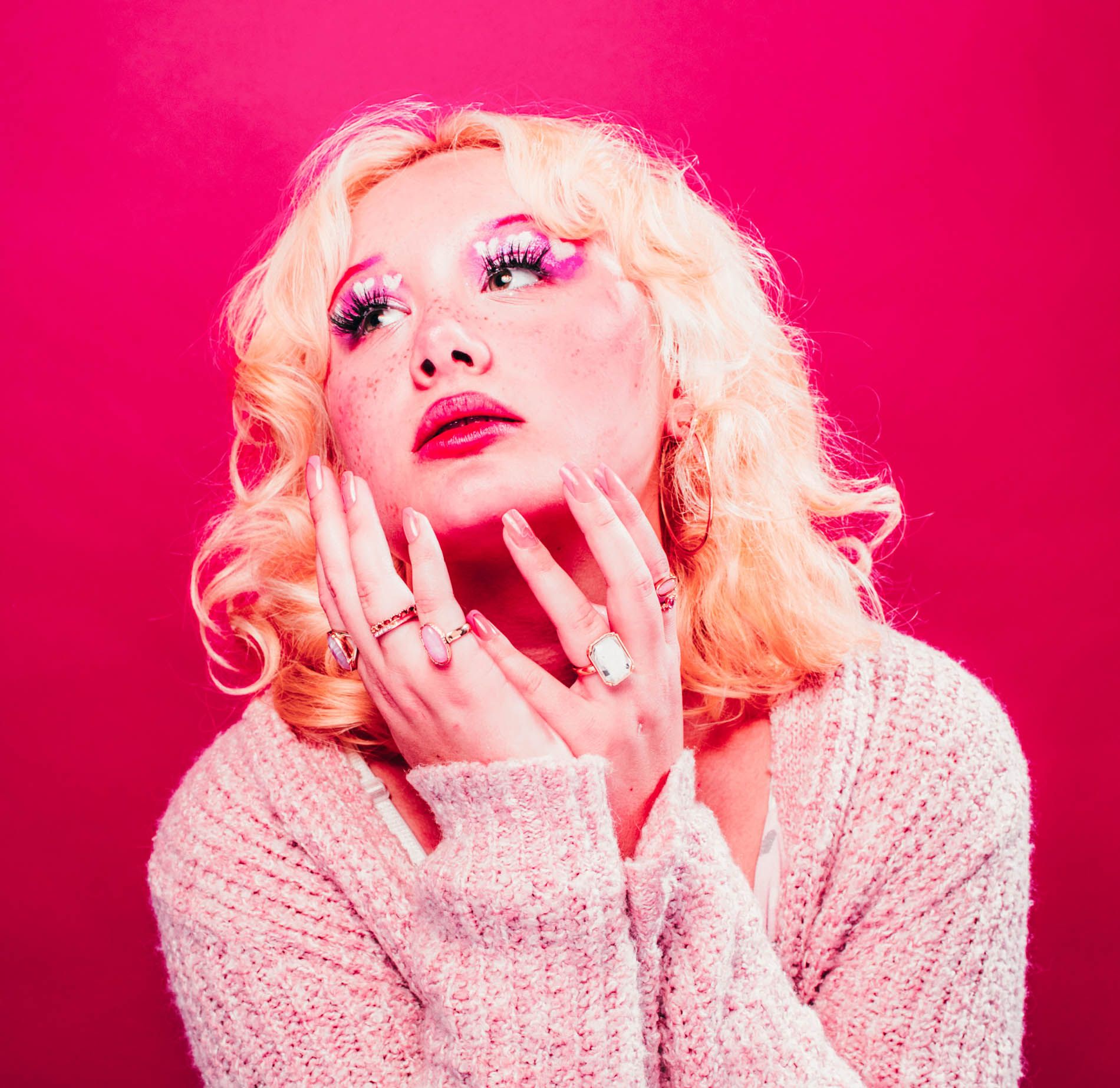 Blonde model posing against a bright pink background, portrait in studio by Asheville photographer Sandlin Gaither