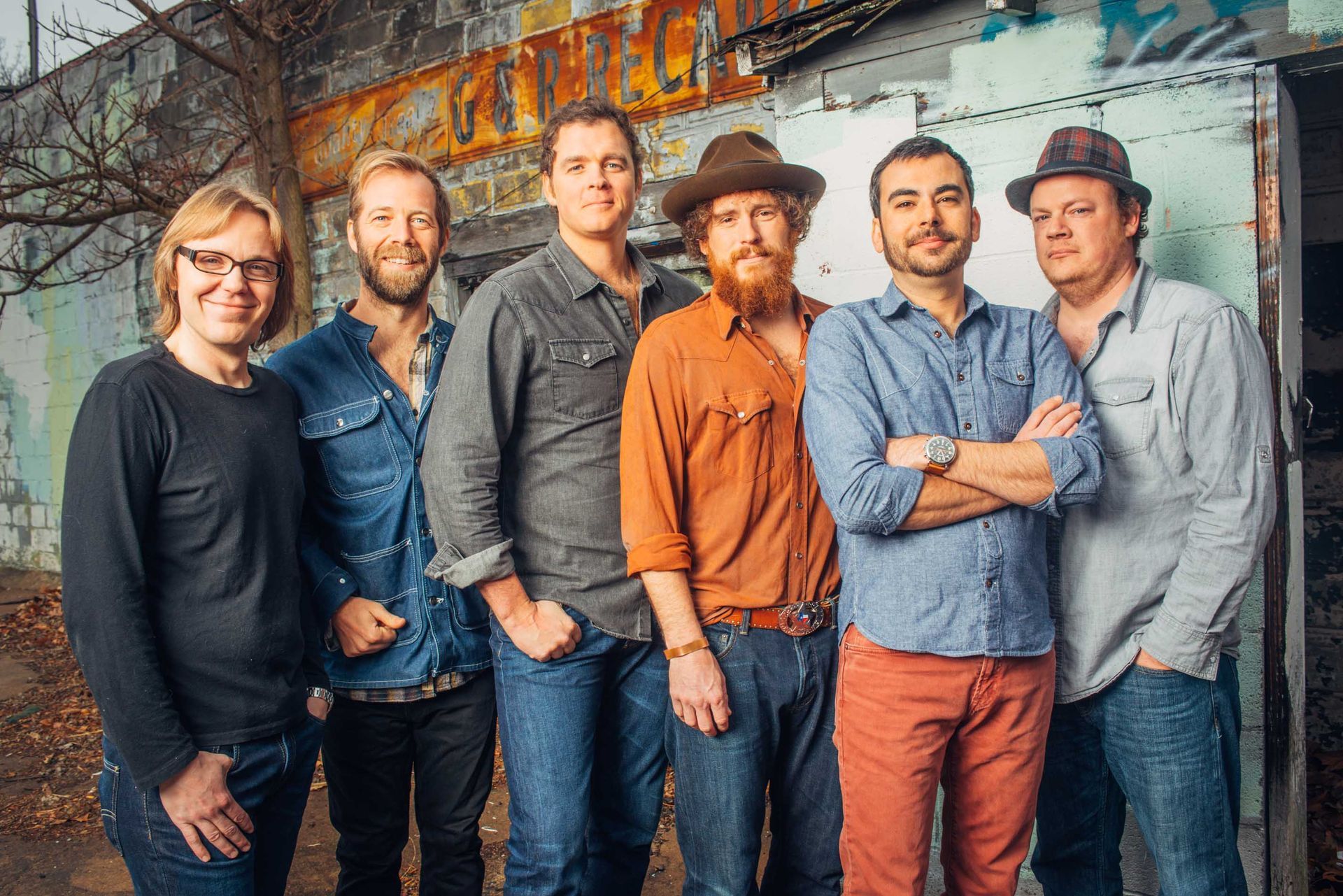bluegrass band steep canyon rangers standing together against a colorful mural, posing casually and smiling, photographed by asheville north carolina music photographer sandlin gaither 