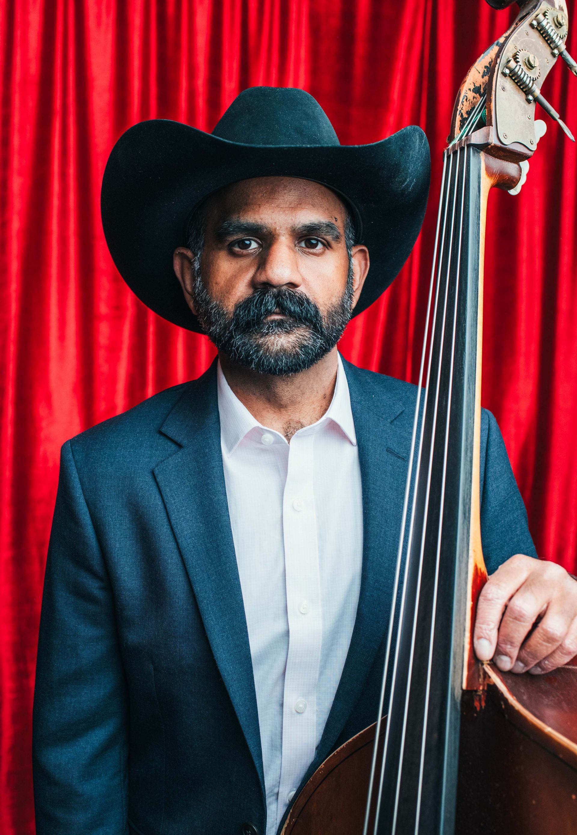 bass player in suit and hat posed with upright bass for music portrait by asheville photographer sandlin gaither 