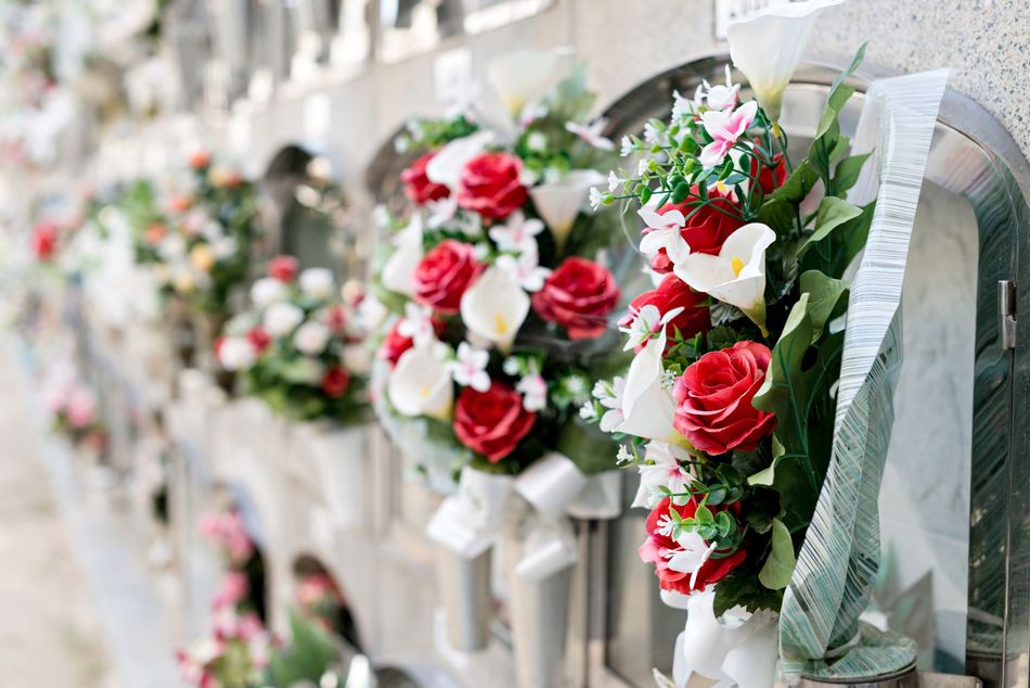 Red and white floral wreaths tied to white chairs in an outdoor ceremony setting