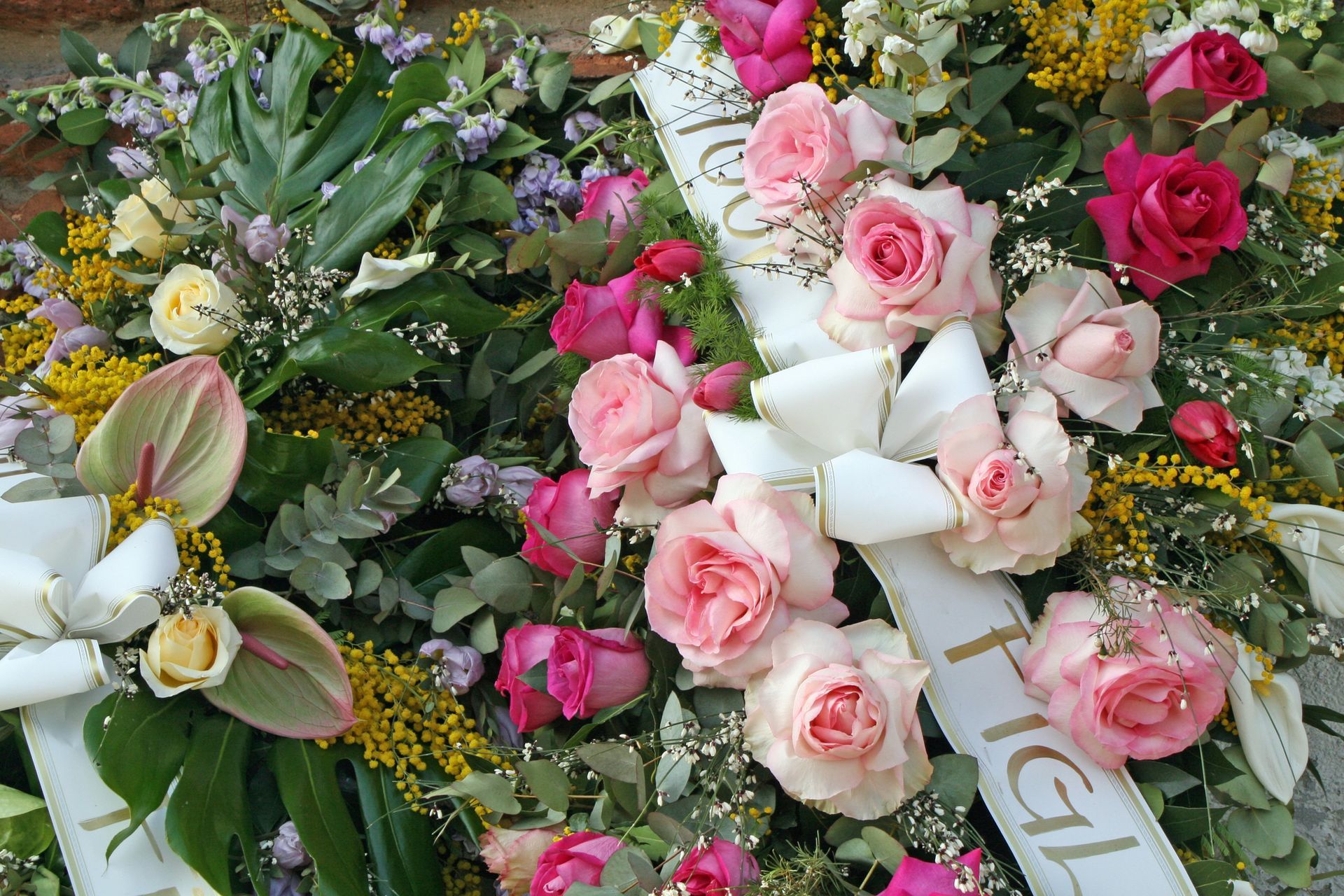 Pink and white roses with greenery arranged in a floral tribute bouquet