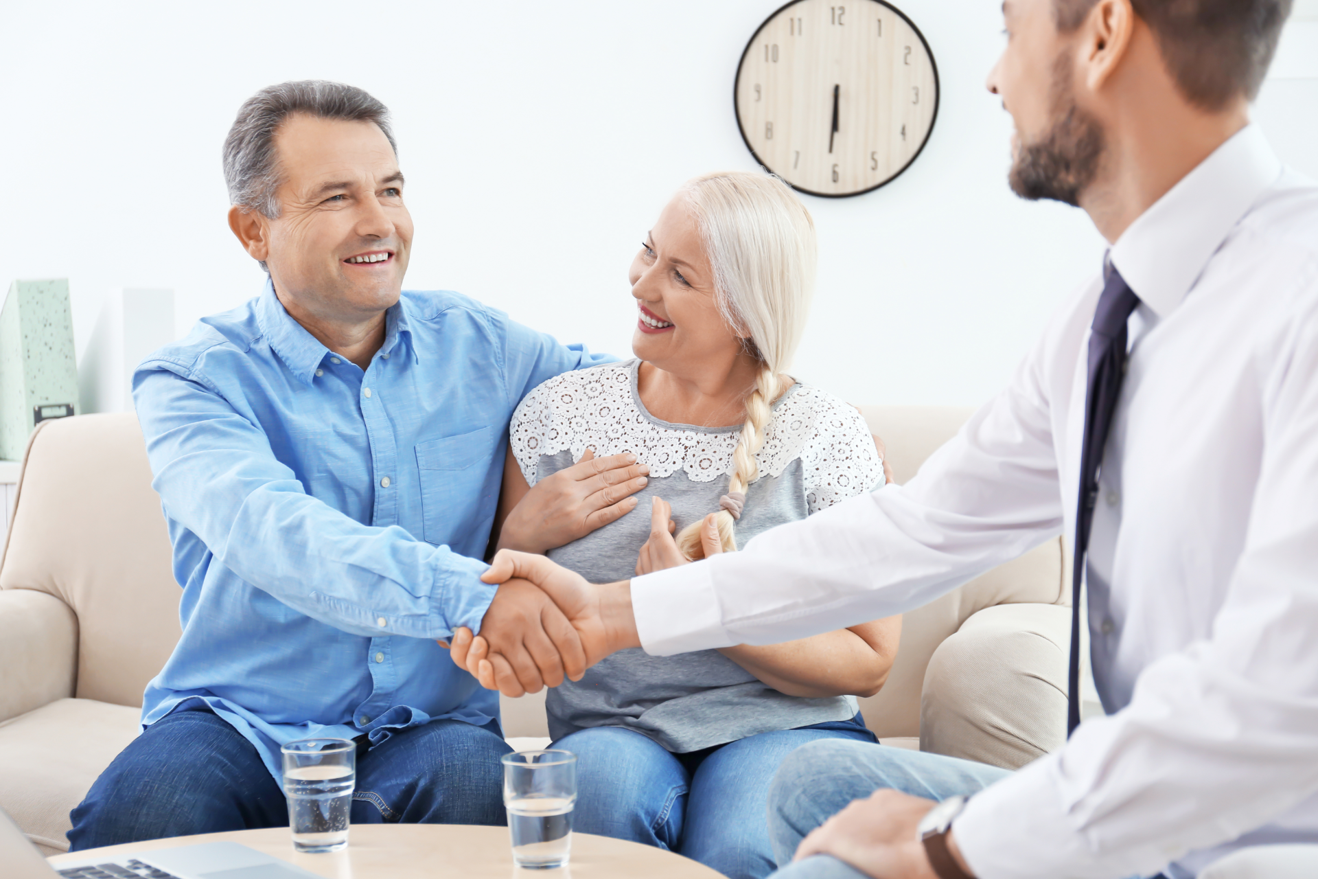 Therapist shaking hands with a seated client while an older couple watches in a bright counseling room