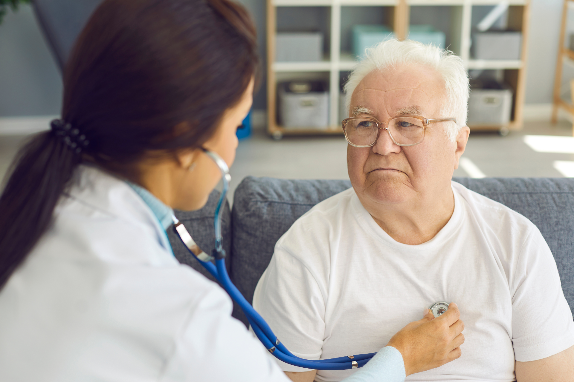 Doctor checking an elderly patient’s chest with a stethoscope in a clinic