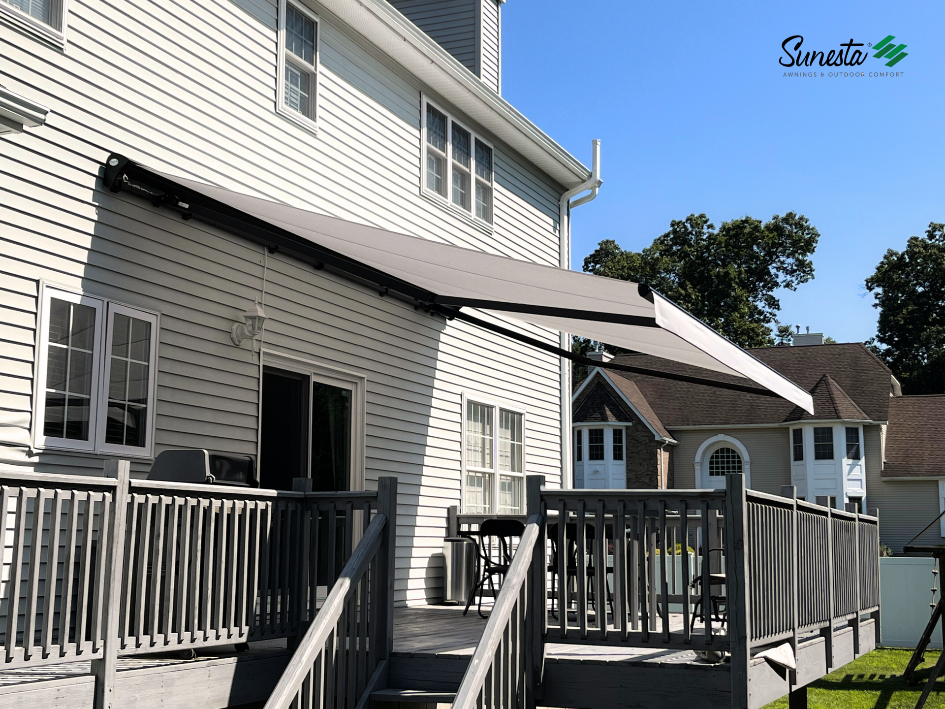 Exterior view of a deck with a retractable awning attached to a house.