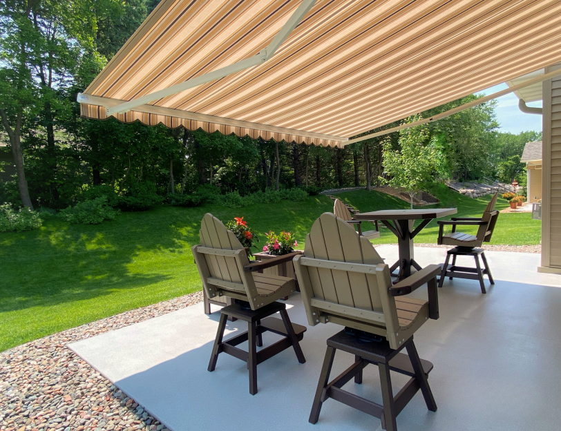 Patio with retractable awning, outdoor furniture on concrete, and green yard.