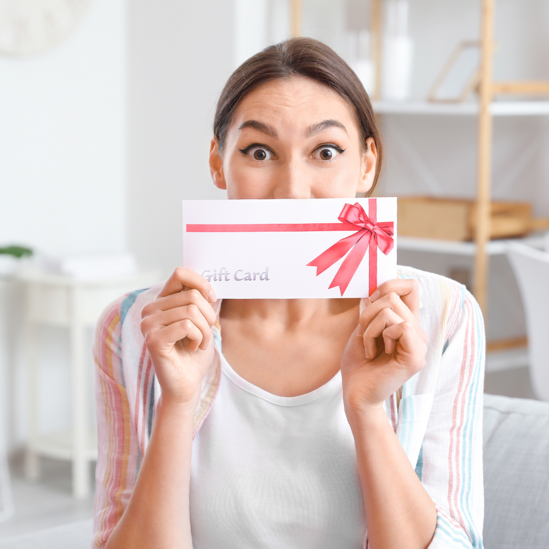 A woman is holding a gift card in front of her face.