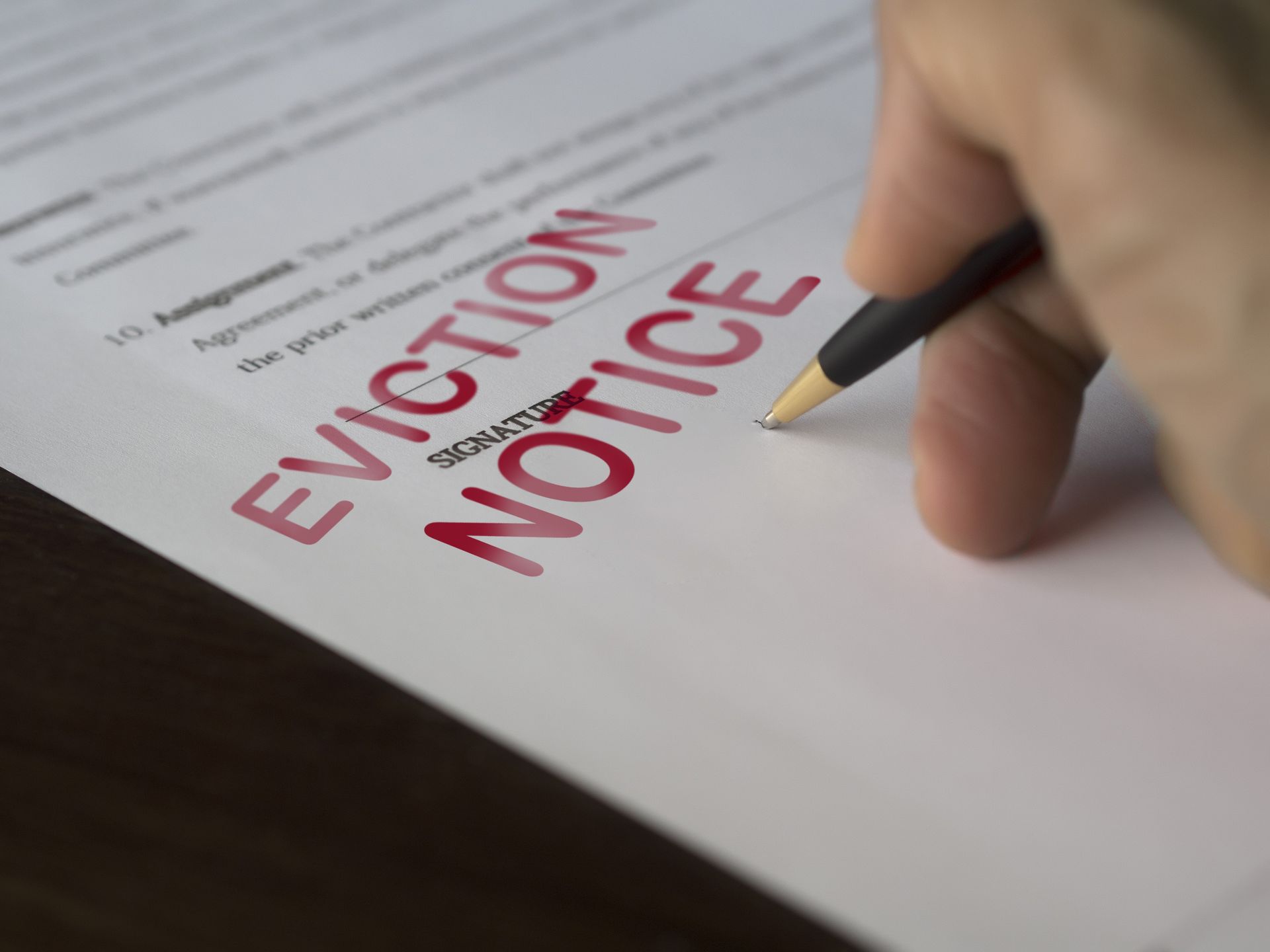 A person is writing an eviction notice on a piece of paper