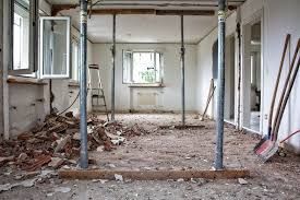 Interior renovation with support beams, debris on the floor, and open windows.