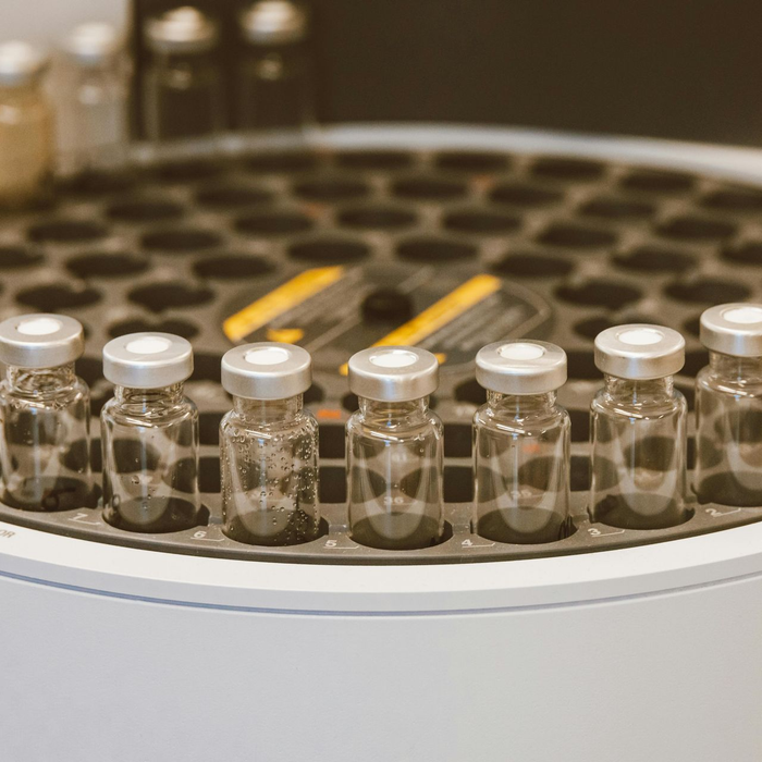 Clear vials in a circular tray, likely in a laboratory, with a blurred background of more vials.