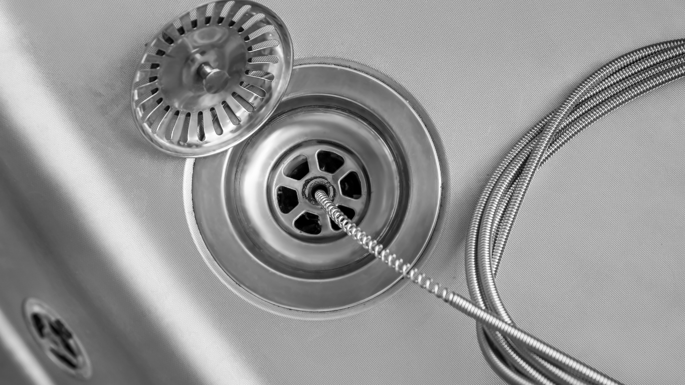 Stainless steel sink drain with plug and strainer, with a braided hose crossing over it.