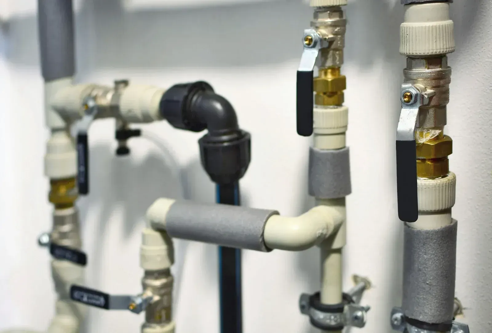 Close-up of white and gray metal pipes with black valves and fittings in an industrial setting