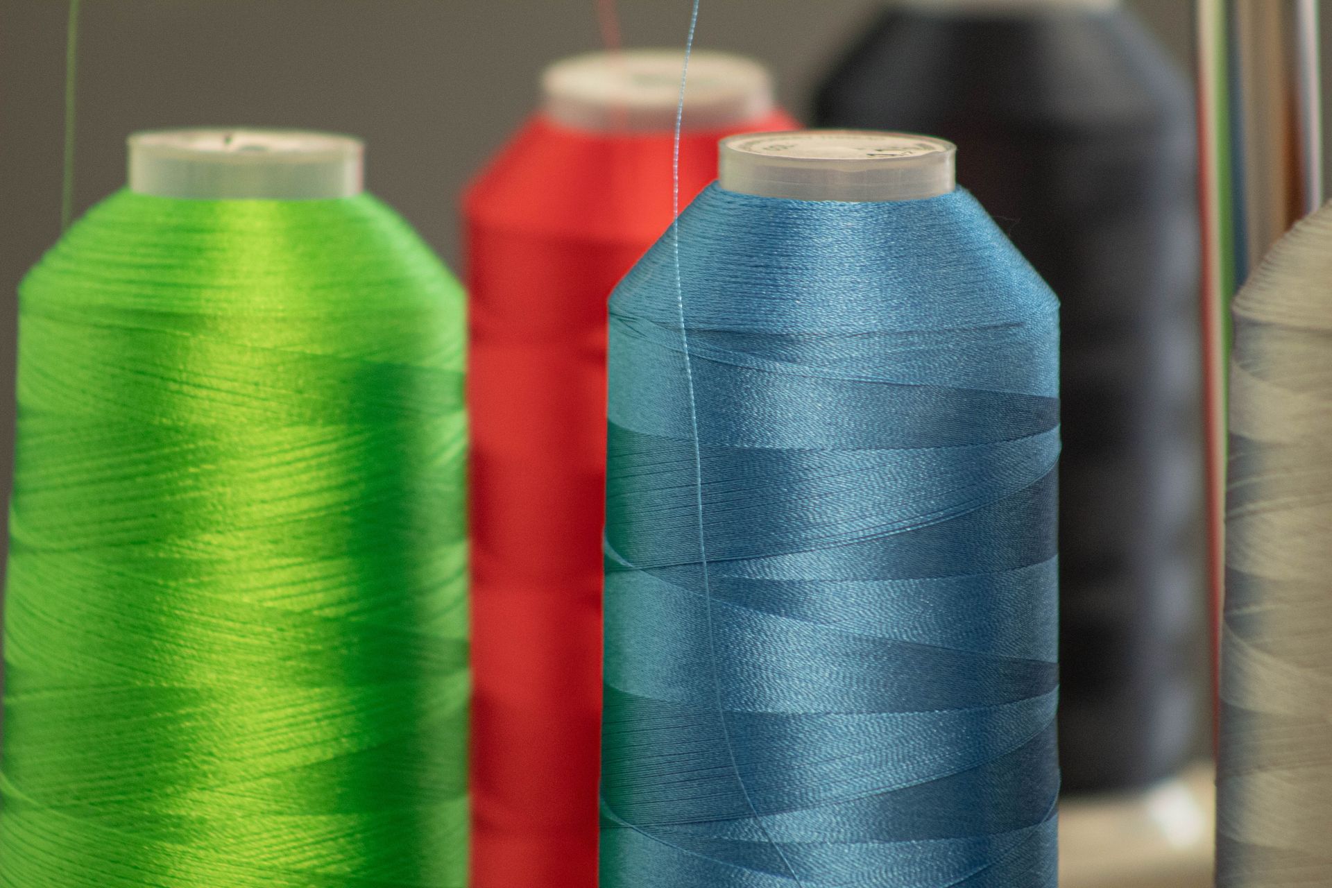 Close-up of colorful thread spools: green, red, blue, and dark gray.