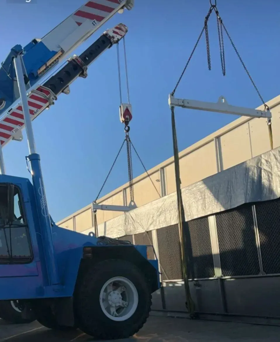 Blue Crane Lifting a Large, Rectangular Object Near a Building — Presto's Cranes & Rigging NQ in Garbutt, QLD