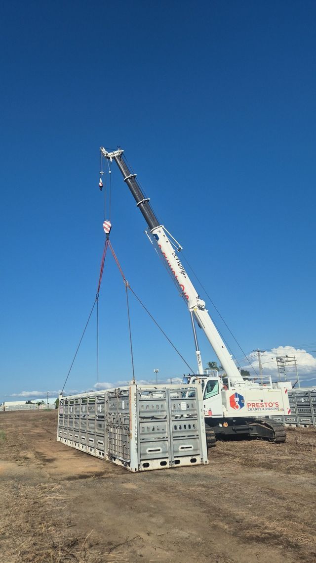 A White Crane Lifting a Metal Livestock Pen on a Construction Site — Presto's Cranes & Rigging NQ in Garbutt, QLD