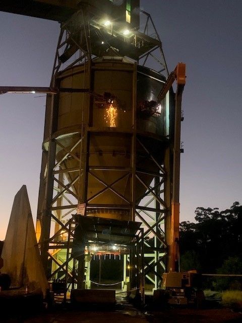 A Large Yellow Silo Is Lit Up At Night — JMG Maintenance & Fabrication In Muswellbrook NSW