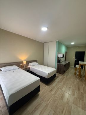 Una pequeña habitación de hotel con dos camas, un microondas y un pequeño comedor.