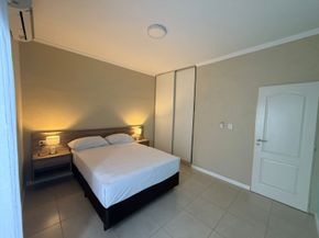 Dormitorio con cama, mesitas de noche, armario, puerta y equipo de aire acondicionado.