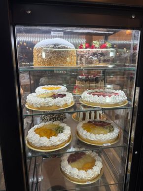 Tortas en vitrina de cristal; glaseado blanco, diversas coberturas de frutas.