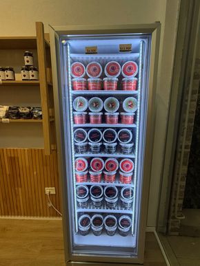 Refrigerador lleno de diversos contenedores de alimentos, iluminado por luces interiores.