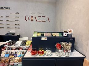 Exhibición de chocolatería con diversas delicias, como barras, caramelos y piruletas. El letrero dice 