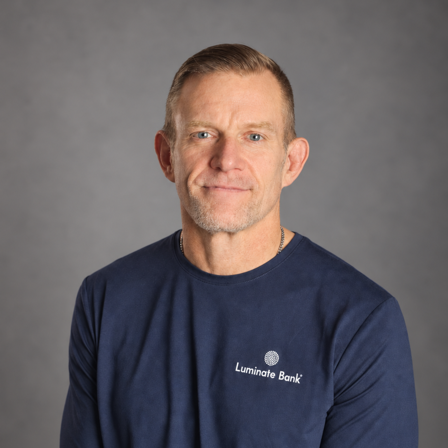 Portrait of a man in a navy crewneck shirt against a gray background