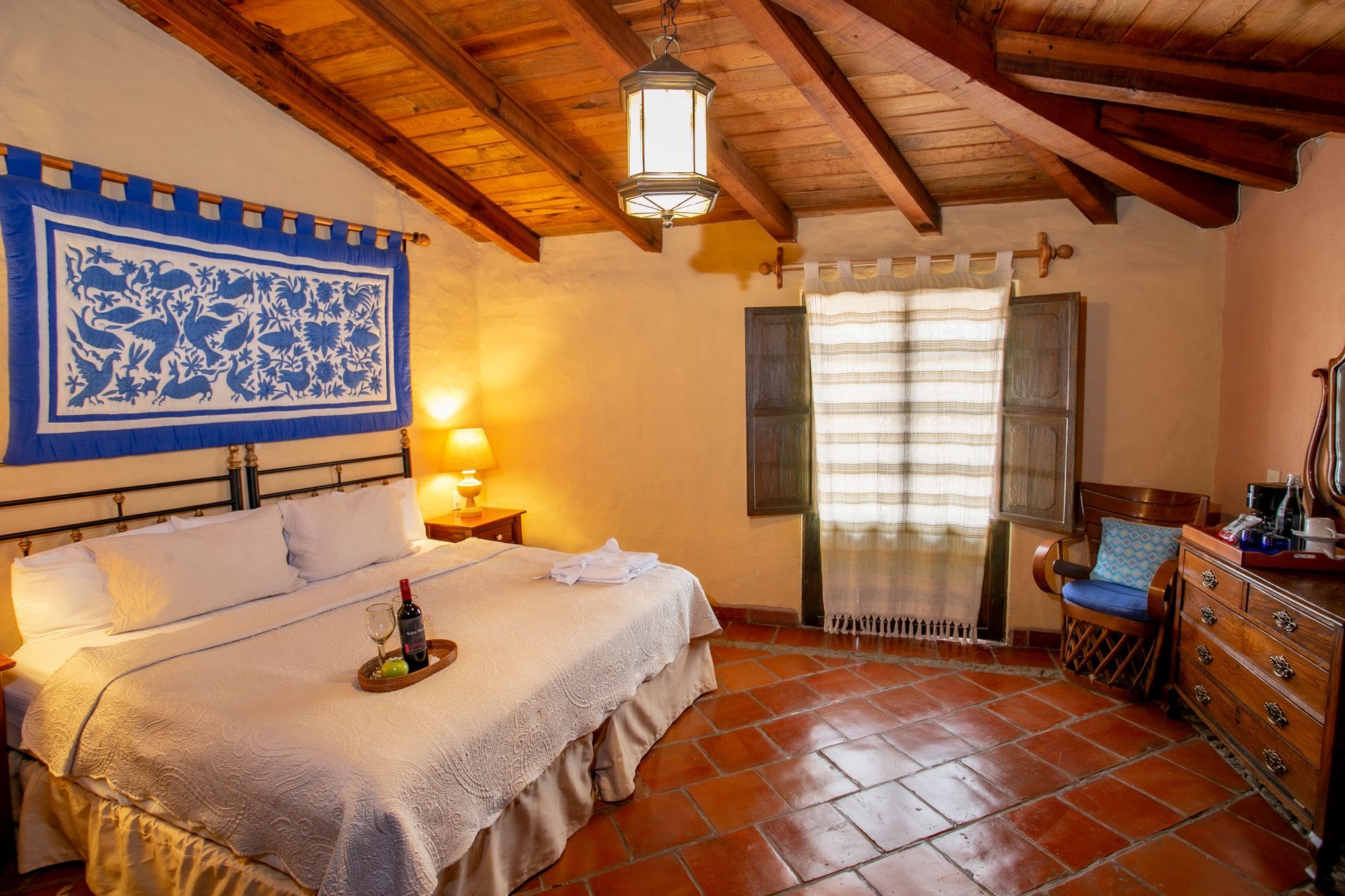 Bedroom with bed, armchairs, wooden wardrobe, and skylight. Earth-toned decor, natural light.