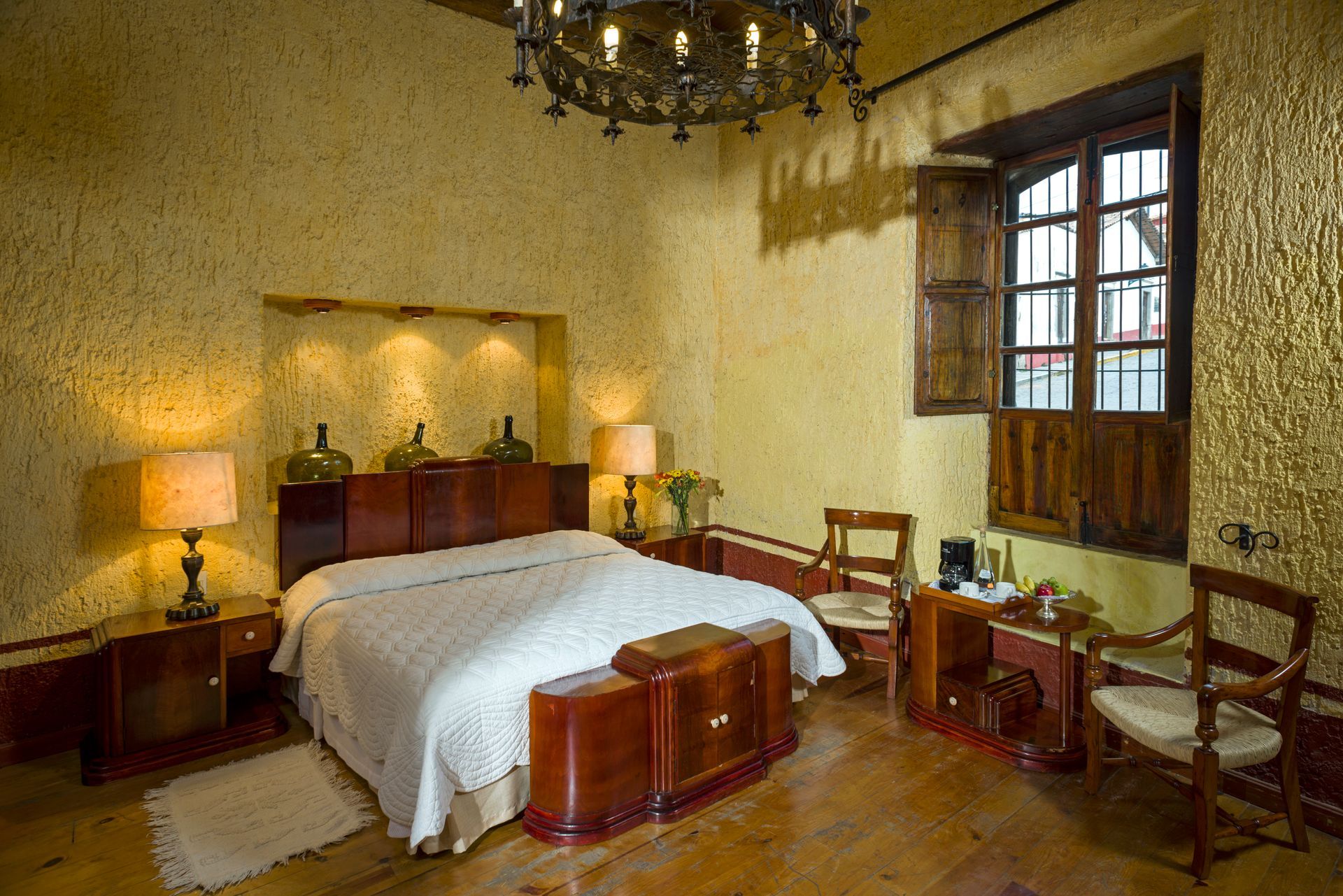 Bedroom with a bed, nightstands, and a door. Exposed wood beams on the ceiling. Light brown floor.