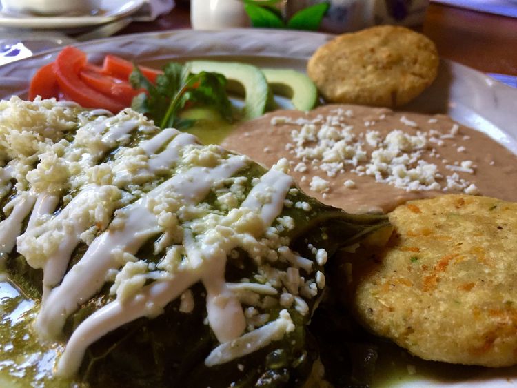 Bandeja mexicana con enchiladas, arroz, frijoles y guarniciones sobre una mesa