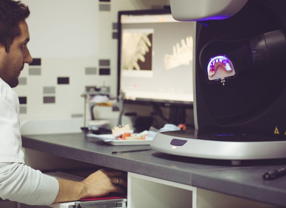 Man using a dental scanner, looking at a computer screen showing dental imagery.