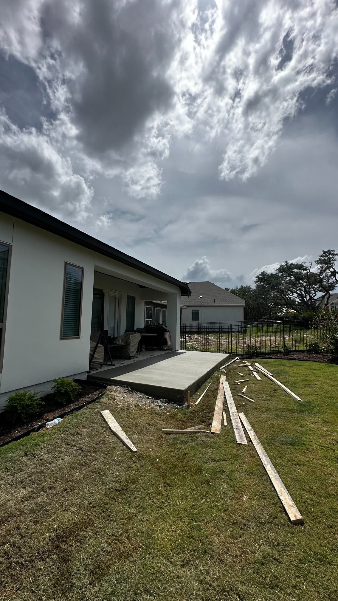 House exterior with a damaged wooden ramp and boards scattered on the grass under a cloudy sky