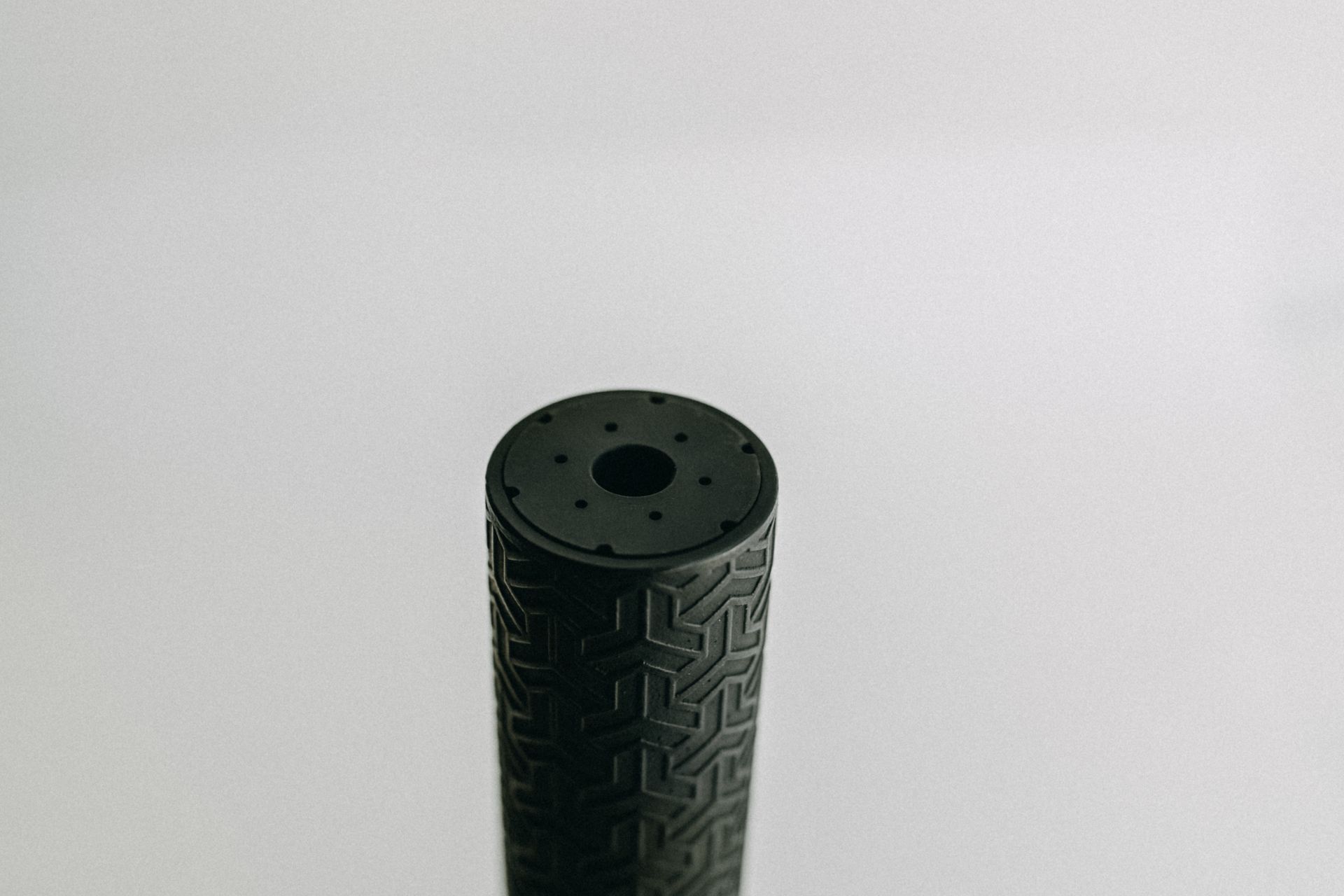 A black cylinder with a hole in the middle is sitting on a white surface.
