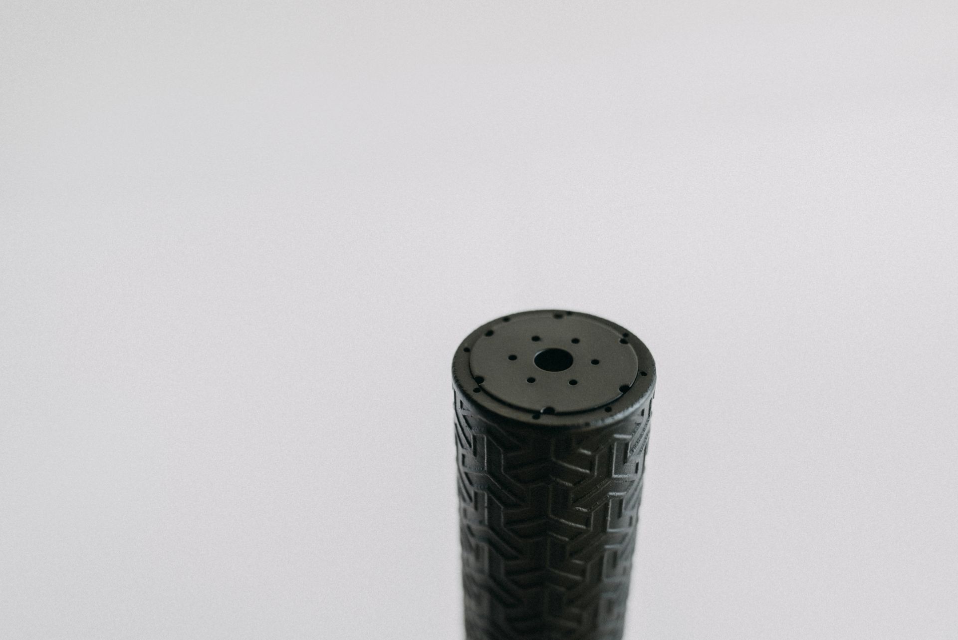 A black cylinder with a hole in the middle is sitting on a white surface.