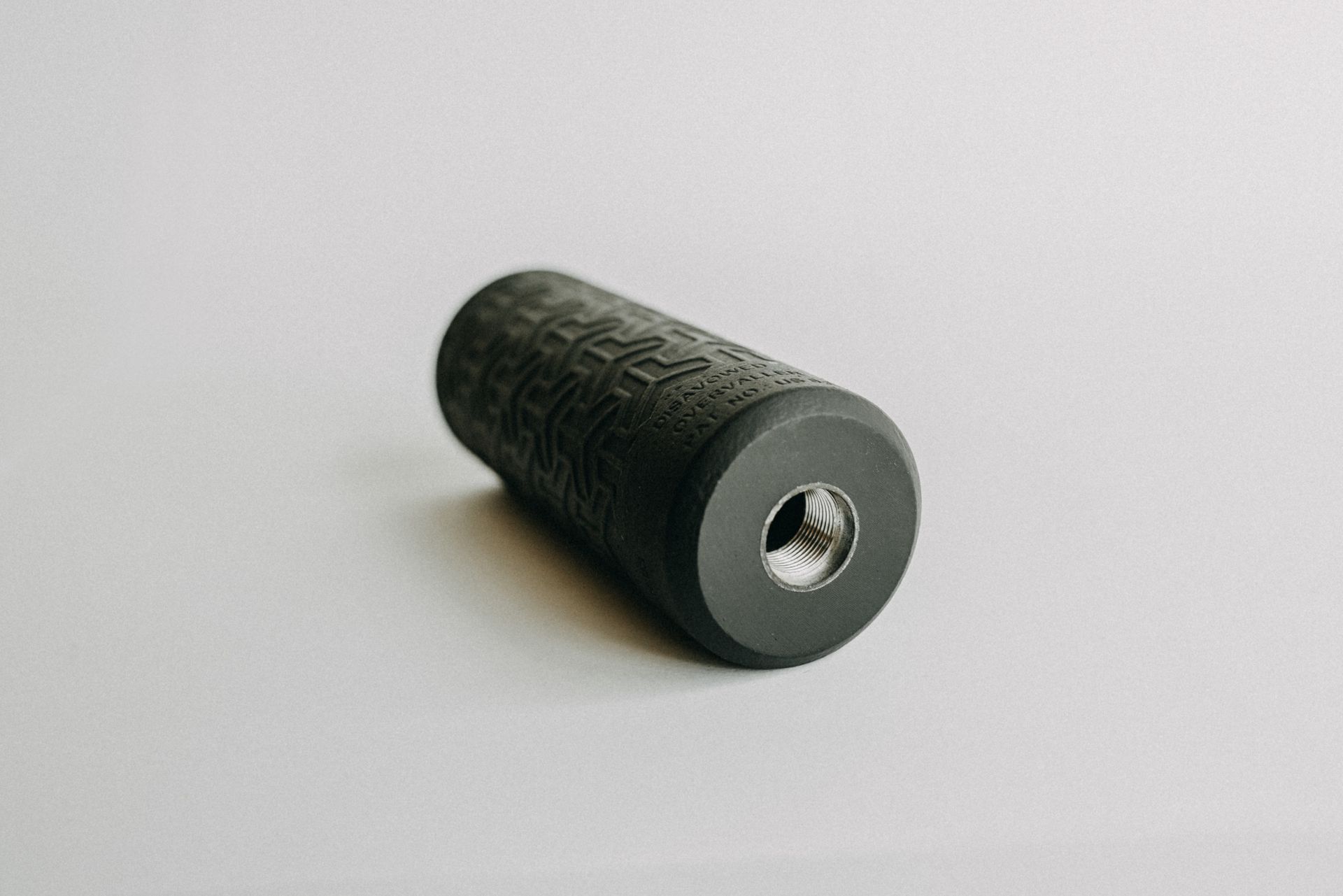 A black object with a hole in the middle is sitting on a white surface.