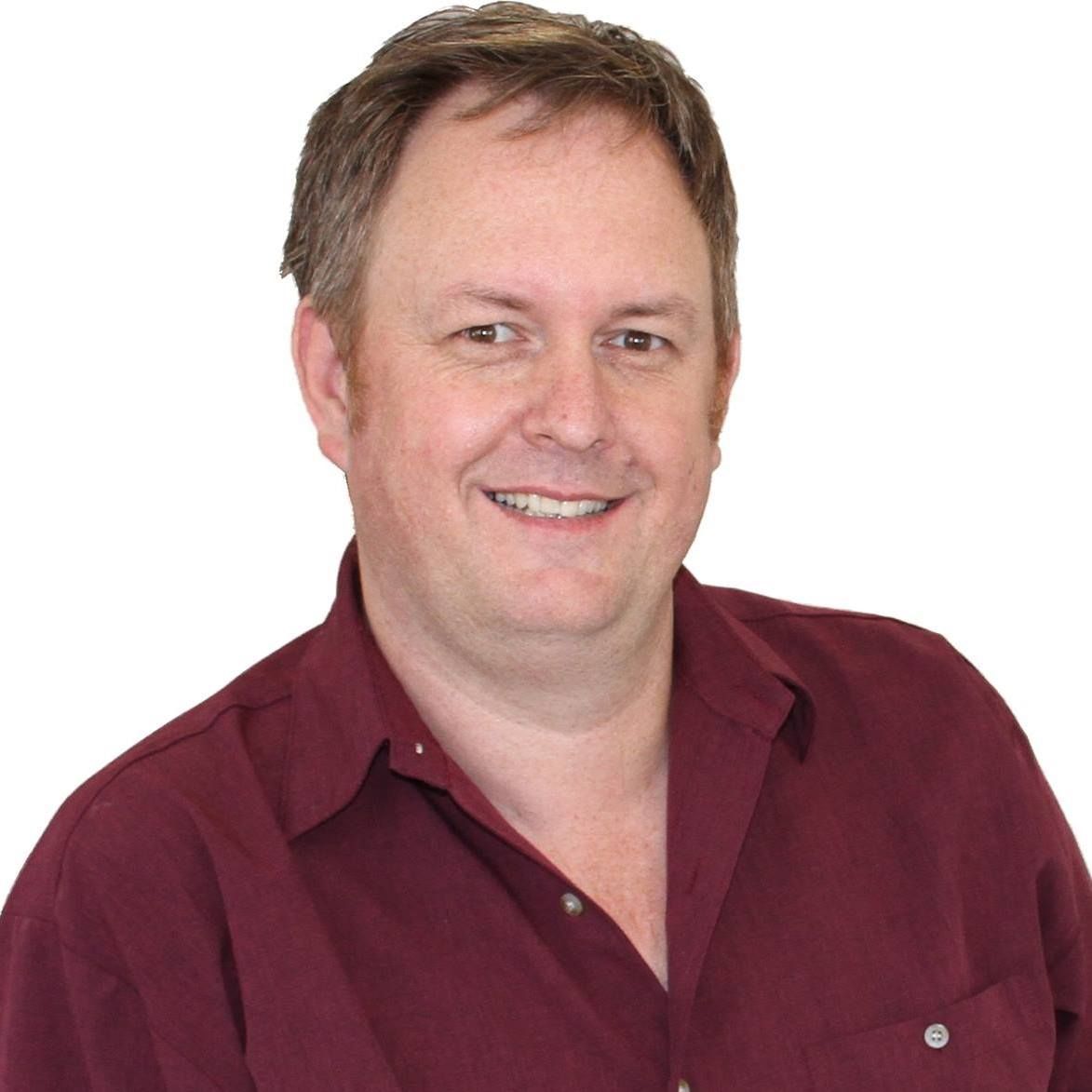 Man with fair skin wearing a maroon shirt smiling at the camera. — Maroochy Denture Clinic In Yandina, QLD