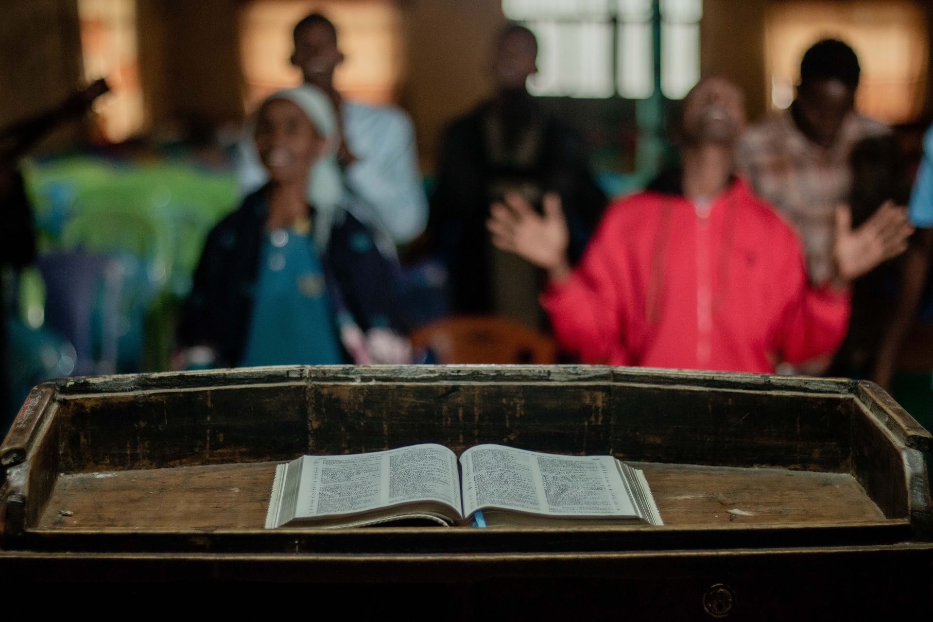 bible on a church pulpit in the foreground with congregation in background