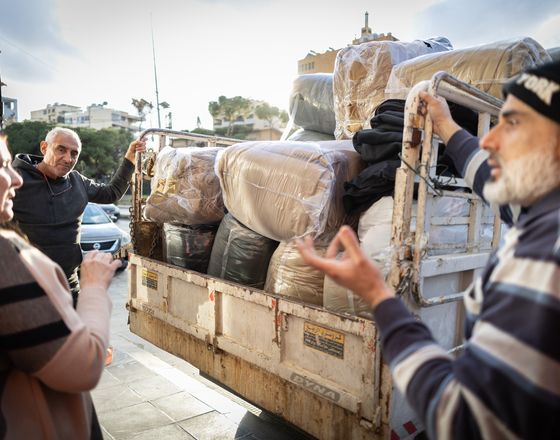 Men loading bundled cargo onto a small truck on a city street