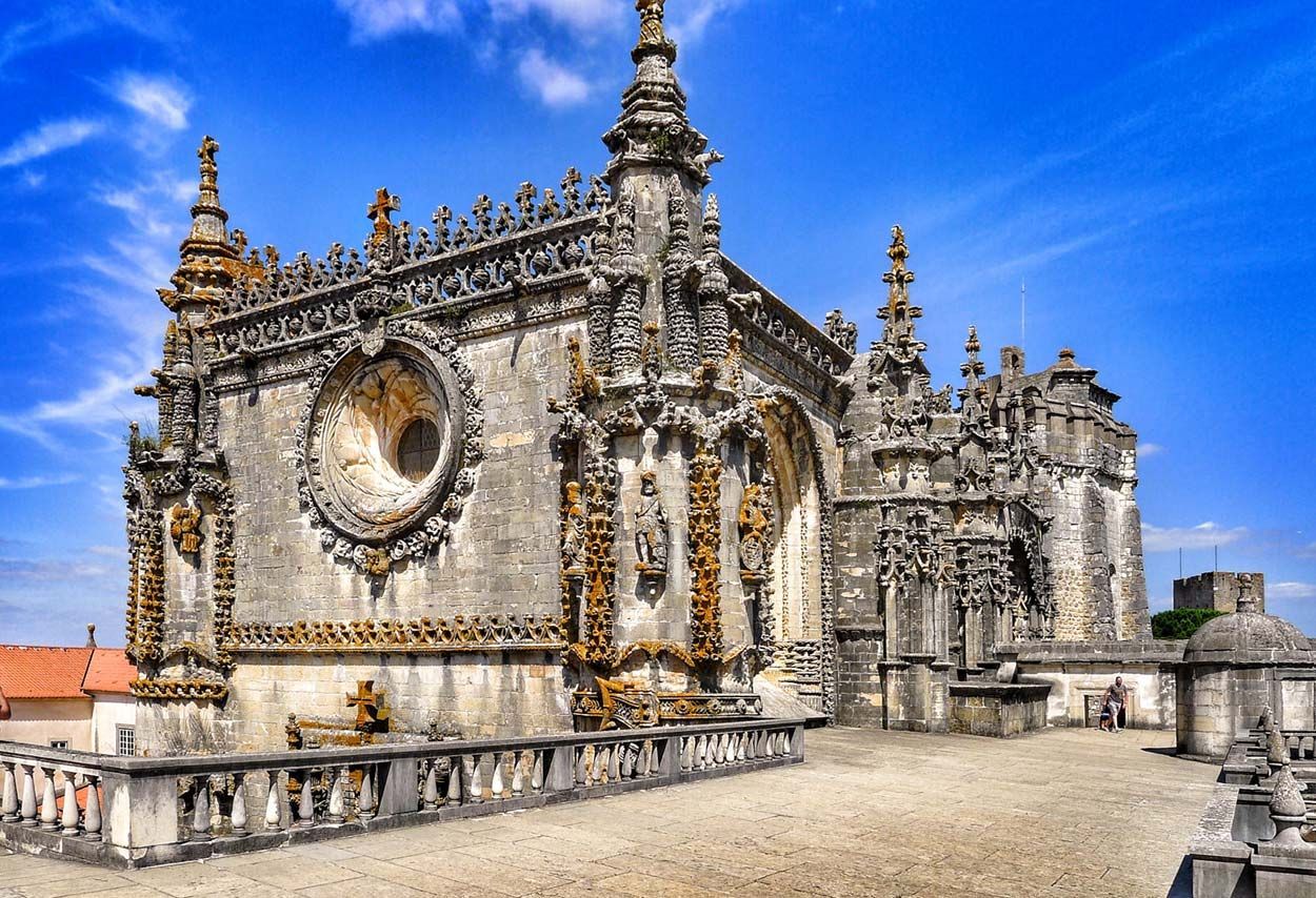 Catedral de pedra ornamentada com entalhes intrincados sob um céu azul brilhante.