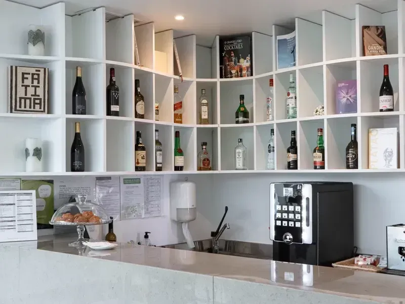 Balcão de bar branco com prateleiras de garrafas e decoração em um café ou bar de vinhos moderno e luminoso.