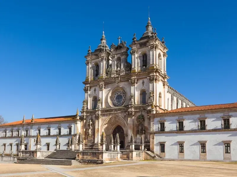 Catedral barroca com torres sineiras gêmeas e entrada em arco sob um céu azul claro.
