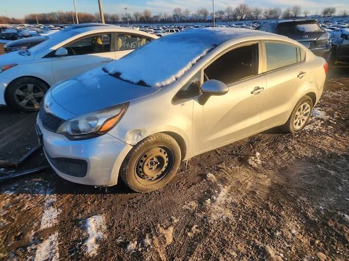 Silver sedan parked on a snowy muddy lot, with a light dusting of snow on the hood and windshield