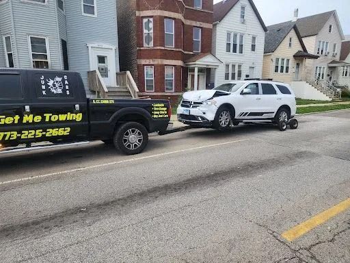 Tow truck towing a white SUV on a residential street in front of houses