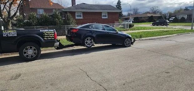 Black sedan angled into the curb on a suburban street beside a parked pickup truck.