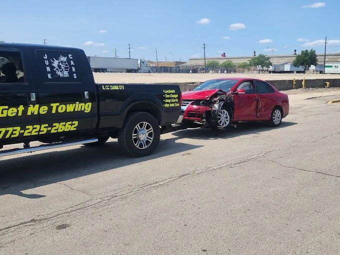 Tow truck towing a red car on a sunny roadside