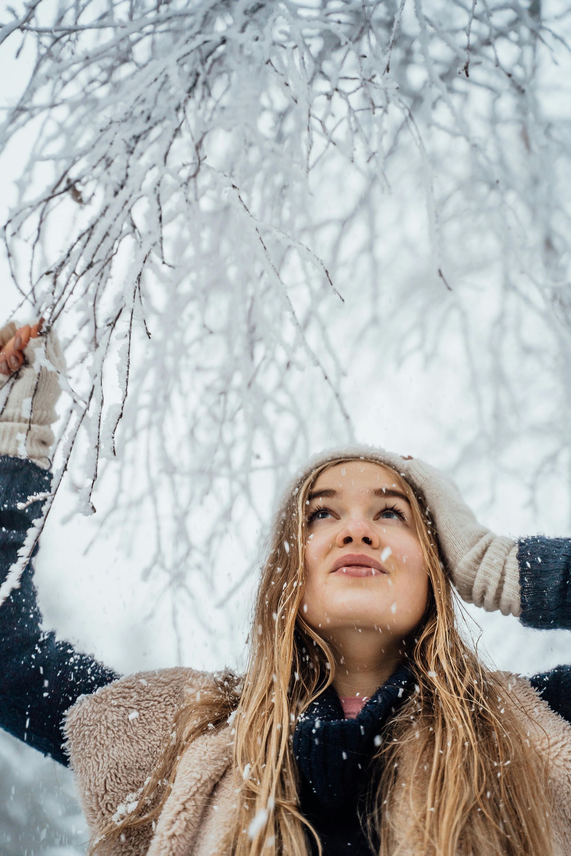 Image of woman looking up while it's snowing outside. Click to read blog post about dry winter skin