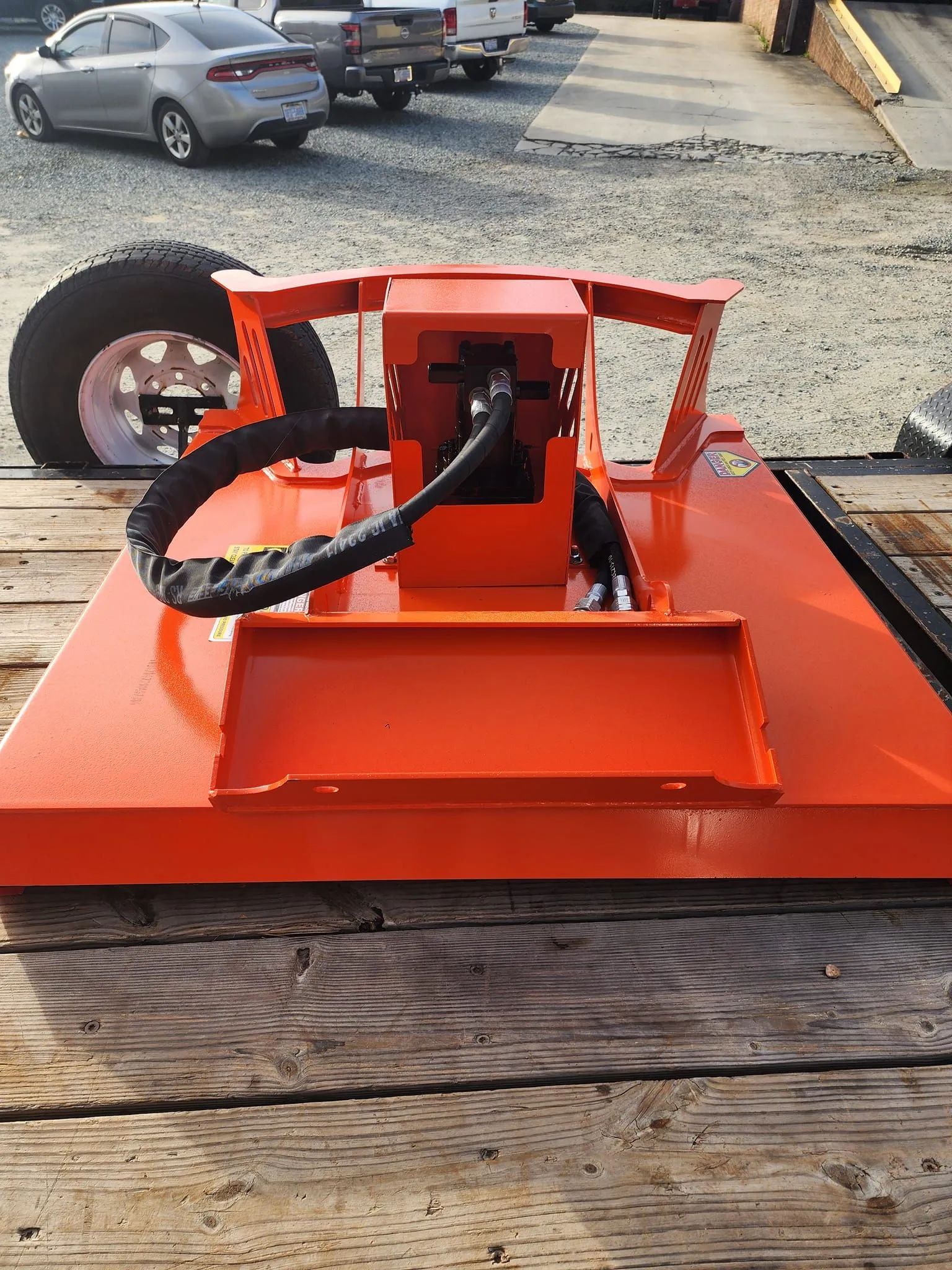 Orange custom mini vehicle with a steering wheel and single front wheel on a wooden table outdoors
