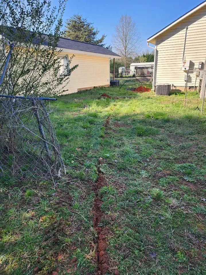 Narrow grassy yard between beige houses with a fence on the left and a red object in the distance.