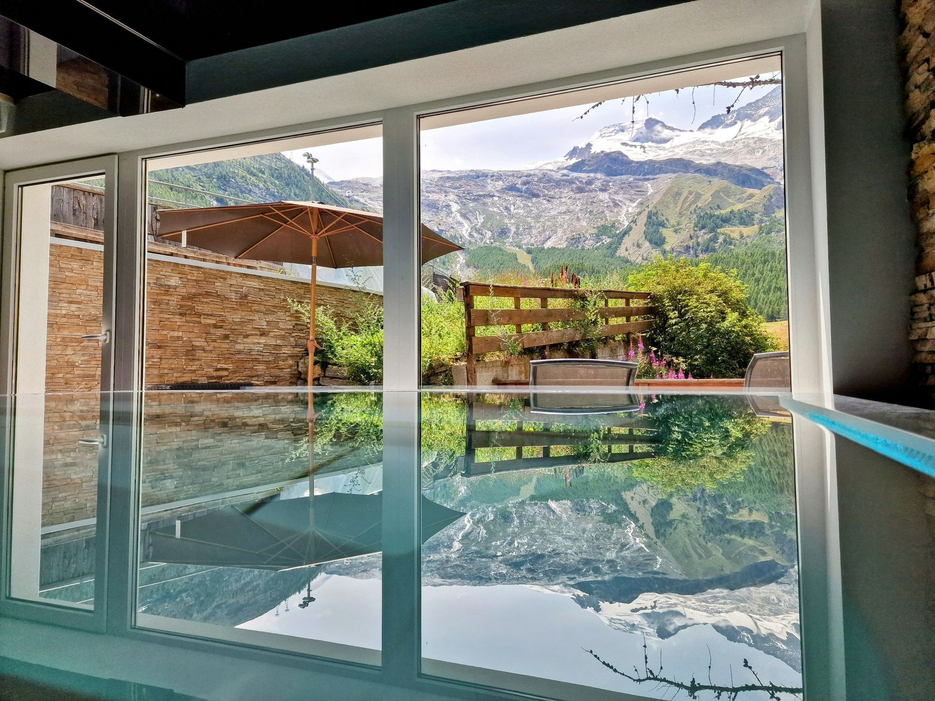 Indoor pool with glass doors reflecting mountains and a patio outside