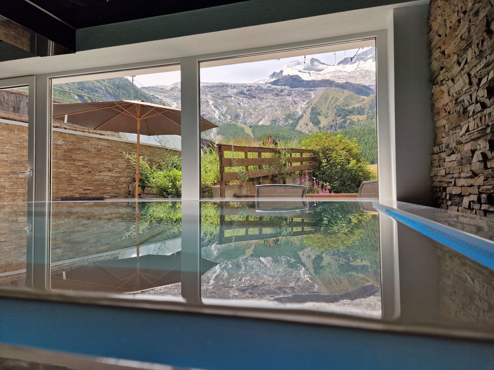 Indoor pool with reflective water, stone walls, and mountain view through large windows