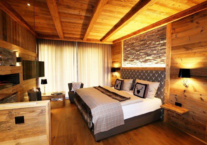 Cozy wooden bedroom with a large bed, warm lighting, and a window with curtains